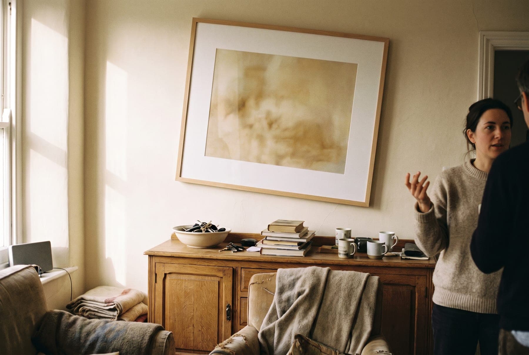 A framed piece hanging above a sideboard in a lived-in room